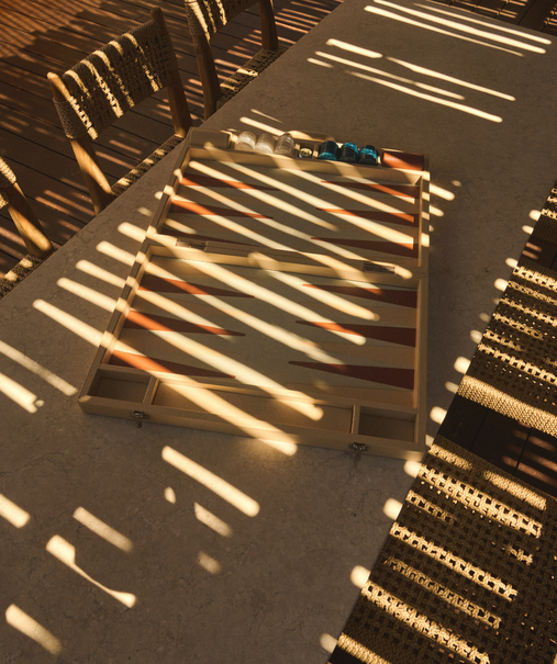 Salon extérieur avec backgammon et chaises en rotin – terrasse Indie Beach, plage Pampelonne
