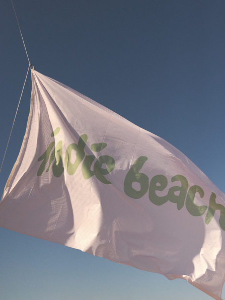 Serviette de plage Indie Beach ray&eacute;e vert et blanc pos&eacute;e sur le sable &ndash; beach club Pampelonne Saint-Tropez