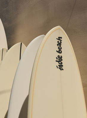 Planches de surf Indie Beach appuy&eacute;es contre un mur en pierre &ndash; beach club restaurant plage Pampelonne