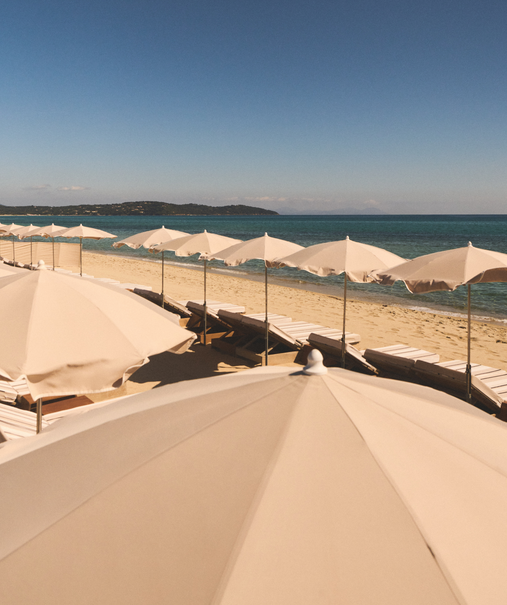 Parasols blancs vus en contre-plongée sous le soleil de Pampelonne – plage Indie Beach, Ramatuelle