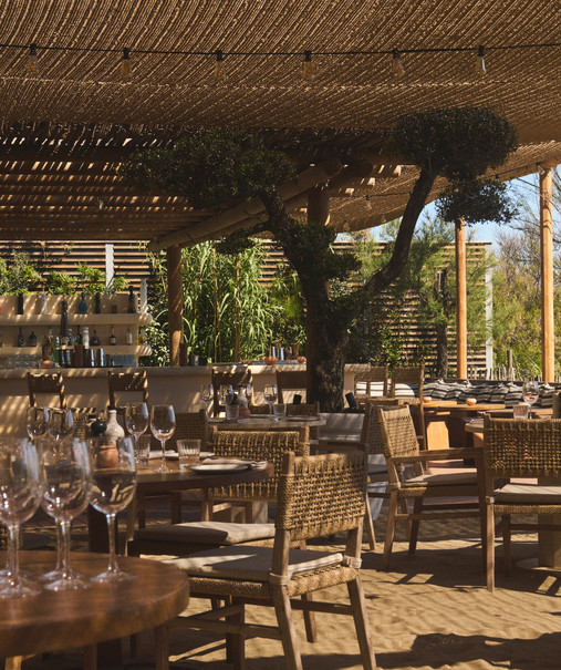 Salle du restaurant plage Pampelonne sous pergola bois, chaises rotin et tables dressées