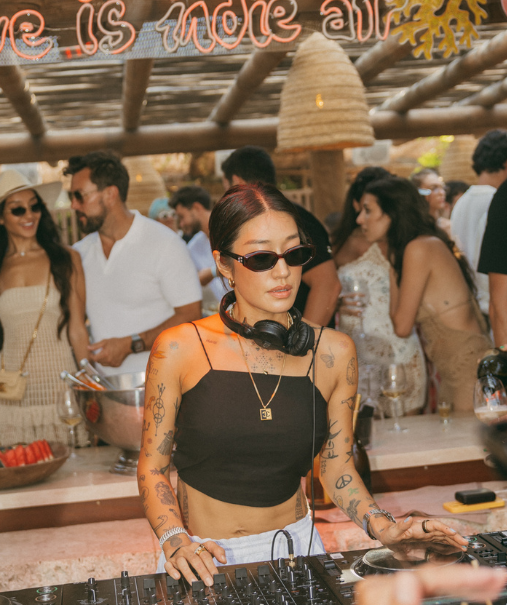 DJ femme tatoués aux platines Pioneer avec pistolet à bulles – club Indie Beach, plage Pampelonne Saint-Tropez